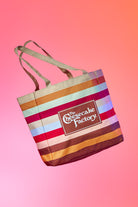 Front of tote bag featuring The Cheesecake Factory's signature stripes and brown boxed logo.